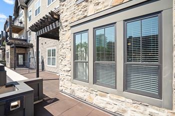 A stone building with a balcony and a window with blinds.